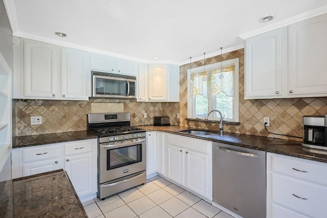 kitchen with stainless steel appliances, a sink, dark stone counters, light tile patterned flooring, and decorative backsplash