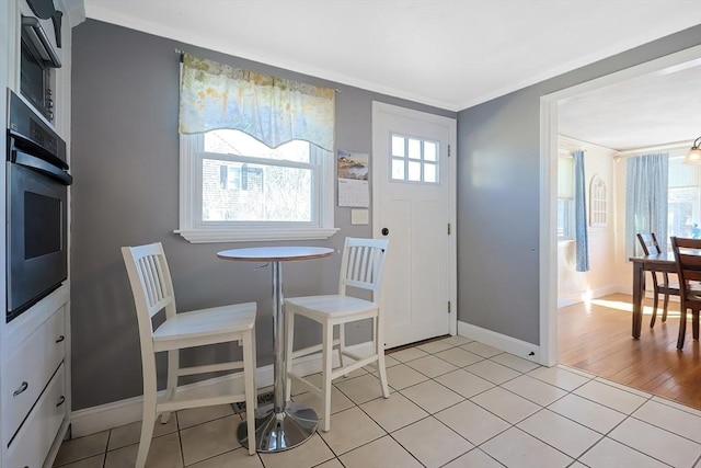 dining room with baseboards, light tile patterned floors, and ornamental molding