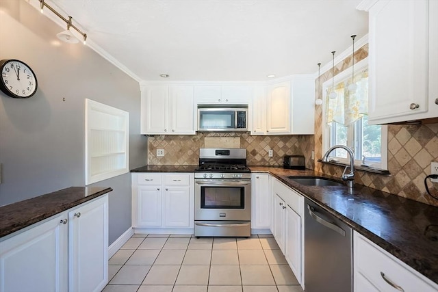 kitchen featuring appliances with stainless steel finishes, a sink, white cabinets, backsplash, and light tile patterned floors