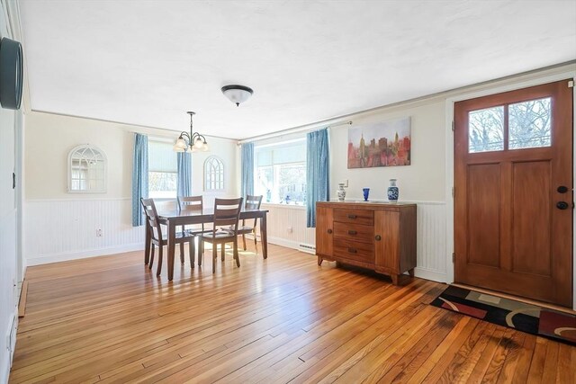 dining space with a chandelier, light wood finished floors, and wainscoting