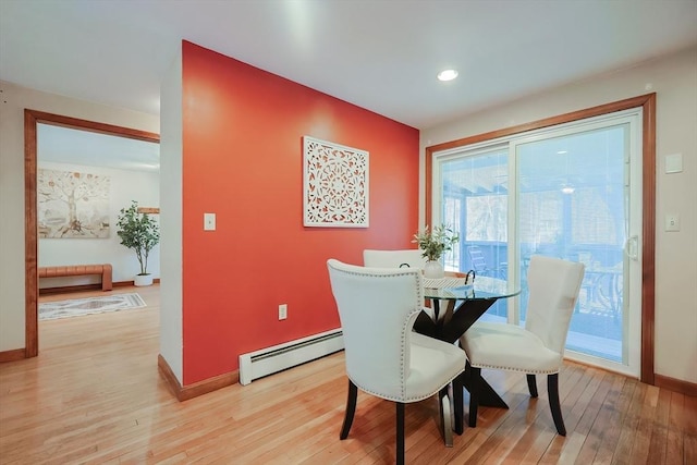 dining space featuring light wood-type flooring, a baseboard heating unit, and baseboards