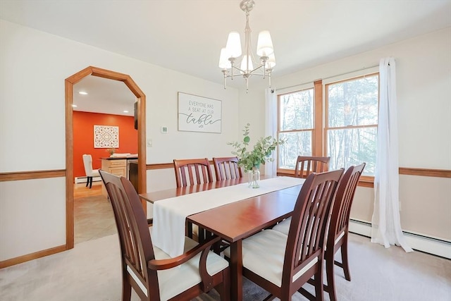 dining space with arched walkways, a chandelier, light colored carpet, and a baseboard radiator