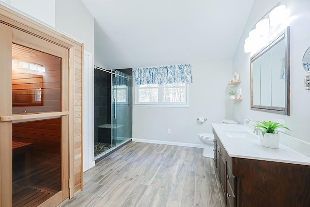 full bath featuring wood finished floors, a shower stall, baseboards, vanity, and vaulted ceiling