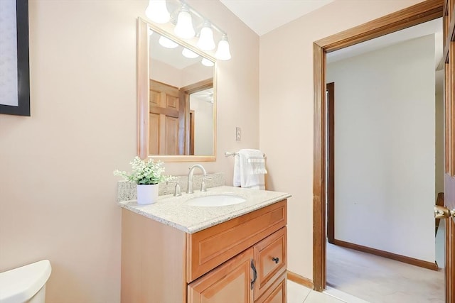 half bath featuring vanity, toilet, and baseboards