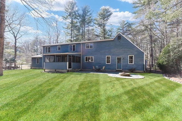 back of property with a lawn, a fire pit, and a sunroom