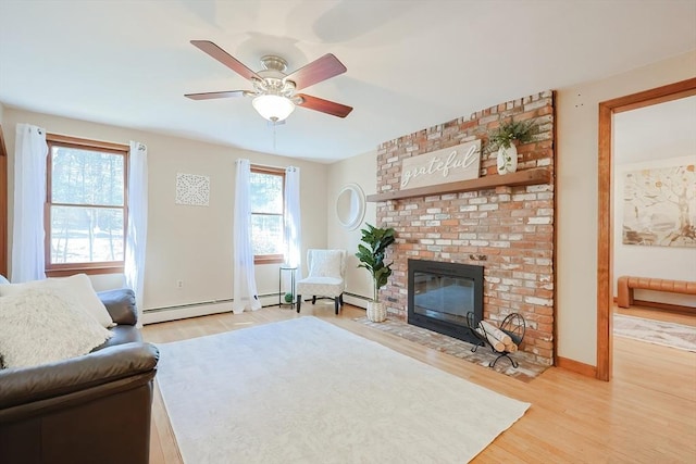 living area featuring a fireplace, light wood-type flooring, a ceiling fan, and a baseboard radiator