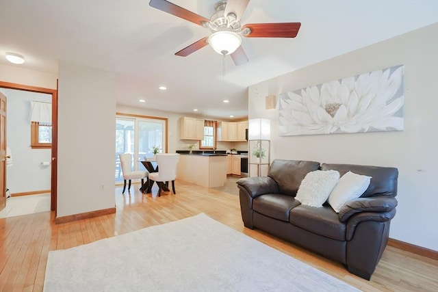 living area with a ceiling fan, recessed lighting, baseboards, and light wood-type flooring