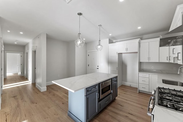 kitchen with sink, white cabinetry, a center island, light hardwood / wood-style flooring, and appliances with stainless steel finishes