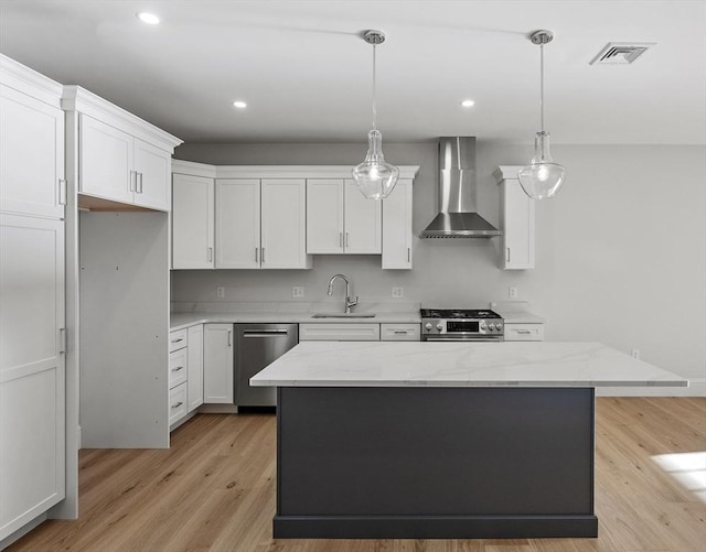 kitchen featuring a kitchen island, appliances with stainless steel finishes, sink, white cabinets, and wall chimney exhaust hood