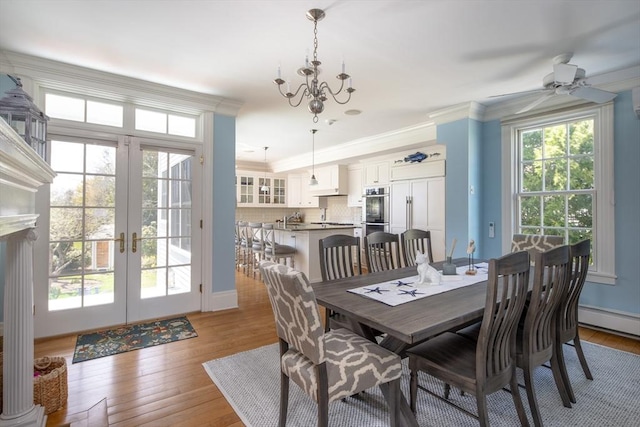 dining space featuring french doors, a ceiling fan, light wood finished floors, crown molding, and a chandelier