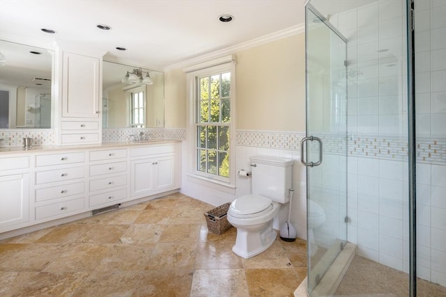 full bath featuring crown molding, tile walls, toilet, a stall shower, and double vanity