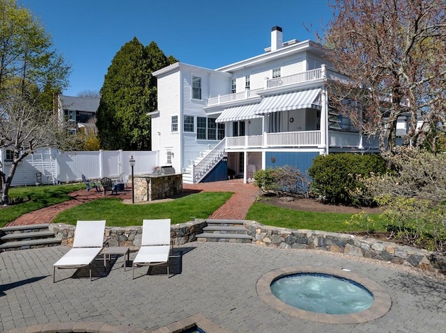 rear view of house with stairway, a patio, an in-ground hot tub, a balcony, and a fire pit