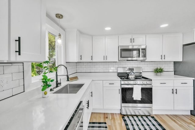 kitchen with appliances with stainless steel finishes, light wood-type flooring, light countertops, and a sink