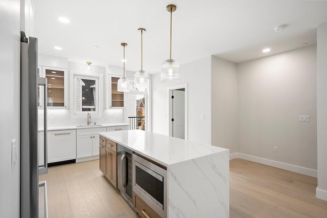21 Ashland Unit 21, Boston, MA 02122 - kitchen featuring a sink, light wood-type flooring, a kitchen island, stainless steel microwave, and glass insert cabinets