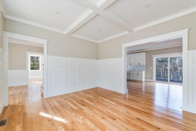 spare room featuring beam ceiling, light hardwood / wood-style flooring, coffered ceiling, and ornamental molding