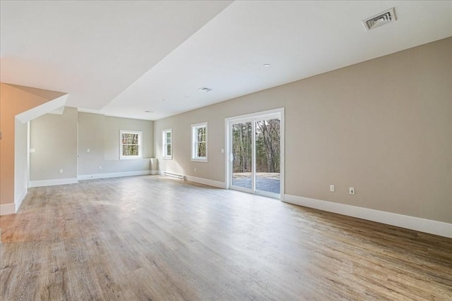 unfurnished living room with a baseboard heating unit and light hardwood / wood-style flooring