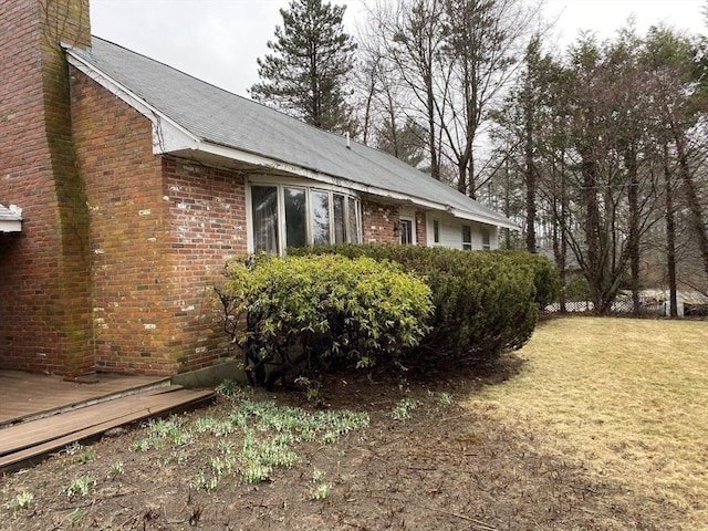 101 Highfields Rd, Abington, MA 02351 - view of side of home featuring a chimney, a wooden deck, brick siding, a lawn, and roof with shingles