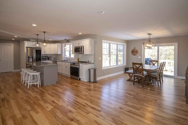 kitchen with light wood finished floors, white cabinetry, appliances with stainless steel finishes, and decorative backsplash