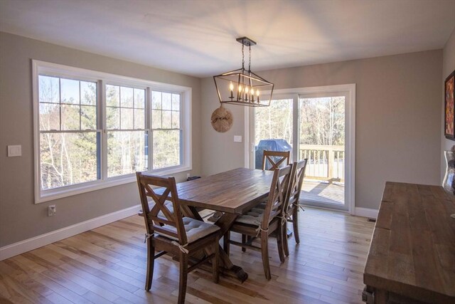 dining room with baseboards, a notable chandelier, and light wood finished floors