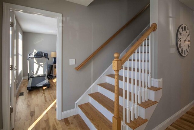 stairway featuring visible vents, baseboards, and wood finished floors