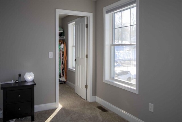 hallway featuring carpet floors, visible vents, and baseboards