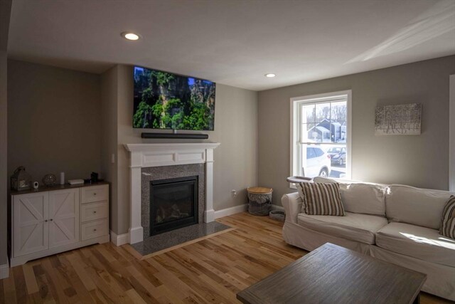 living room with a fireplace with flush hearth, recessed lighting, light wood-style floors, and baseboards