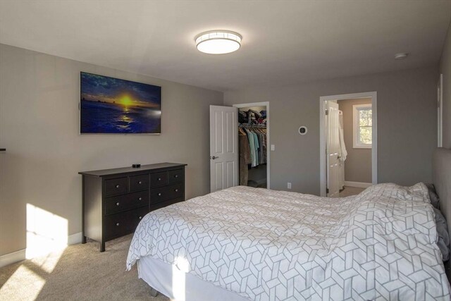 bedroom with light carpet, a spacious closet, and baseboards