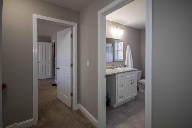 bathroom with baseboards, vanity, and toilet