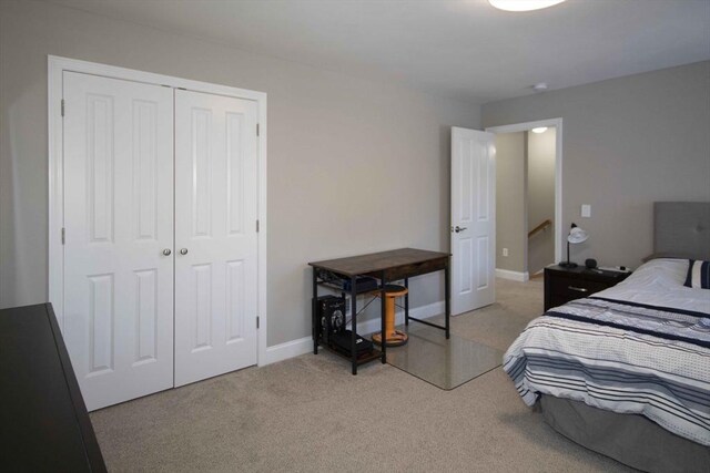 bedroom with light carpet, a closet, and baseboards