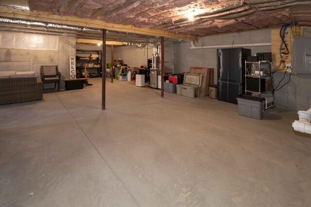 unfinished basement with freestanding refrigerator