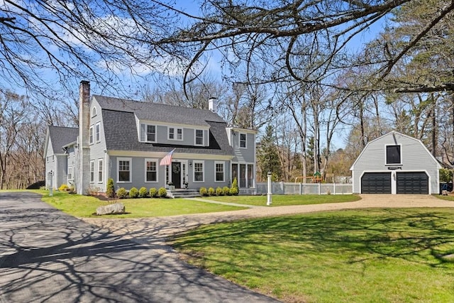 colonial inspired home with a gambrel roof, fence, a chimney, and a detached garage