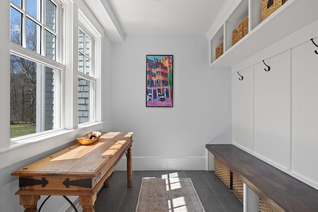 mudroom with dark tile patterned floors and baseboards