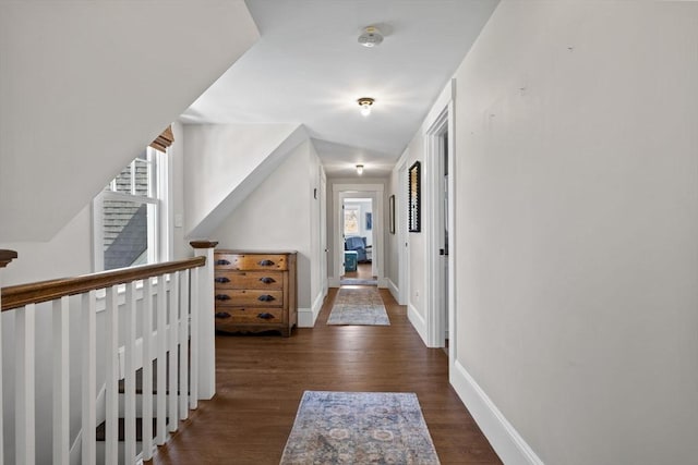 hallway featuring baseboards, wood finished floors, and an upstairs landing