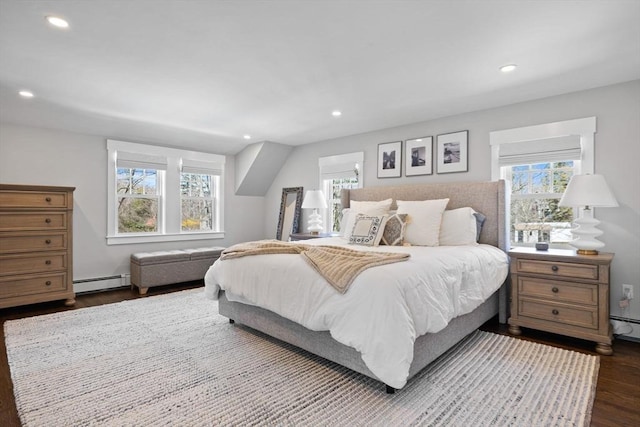 bedroom with multiple windows, a baseboard heating unit, and dark wood-type flooring