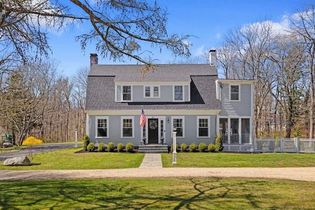 dutch colonial featuring a chimney, roof with shingles, a front yard, a sunroom, and fence