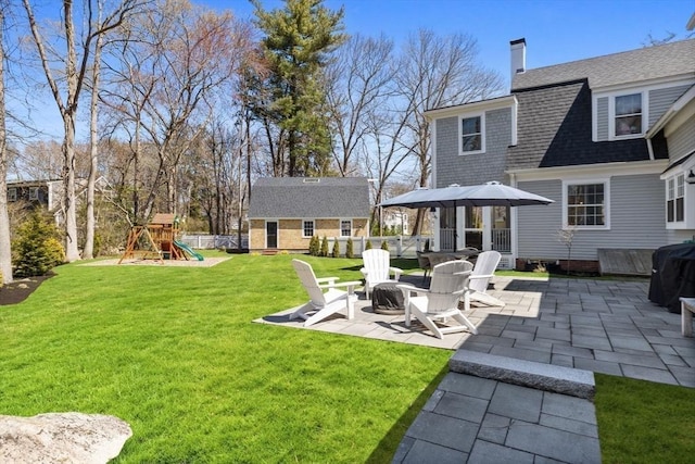 rear view of house with a lawn, a patio, a chimney, and a playground