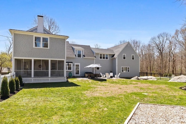 back of property with a lawn, a patio, a chimney, and a sunroom