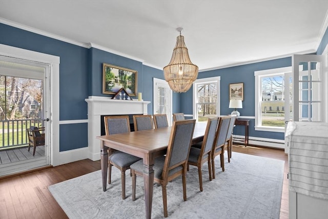 dining room featuring wood finished floors, baseboards, a baseboard heating unit, and a notable chandelier