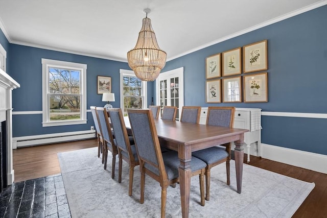 dining room with ornamental molding, baseboard heating, wood finished floors, and a notable chandelier