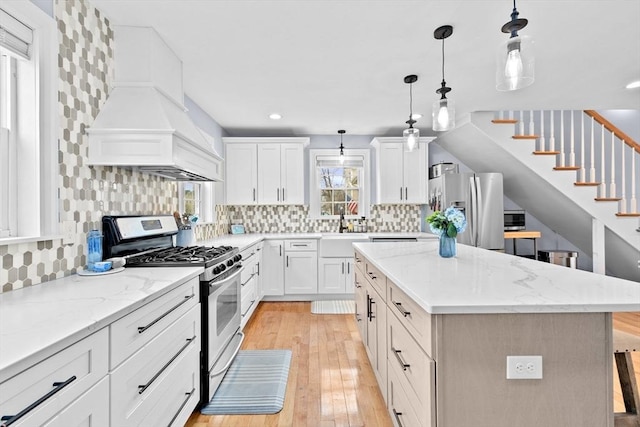 kitchen with stainless steel appliances, a kitchen island, light wood finished floors, and tasteful backsplash