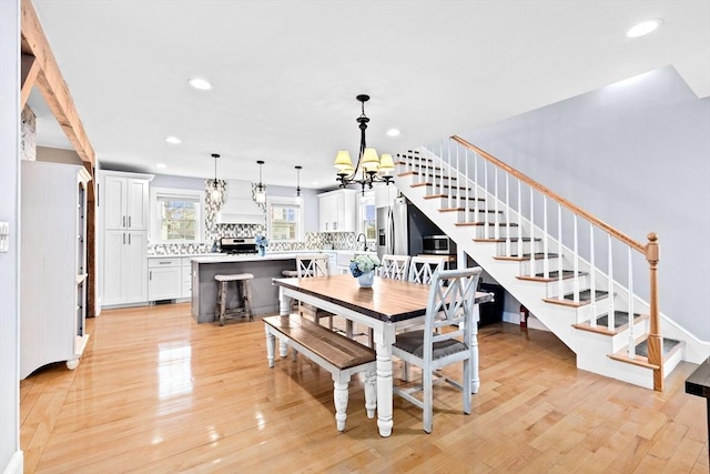 dining room featuring light wood-style floors, stairway, a notable chandelier, and recessed lighting