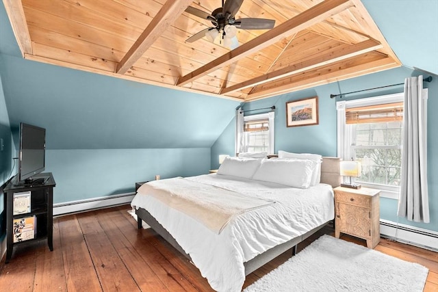 bedroom with a baseboard heating unit, hardwood / wood-style floors, and multiple windows