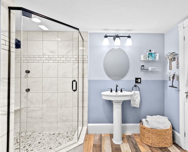 bathroom with baseboards, wood finished floors, and a shower stall