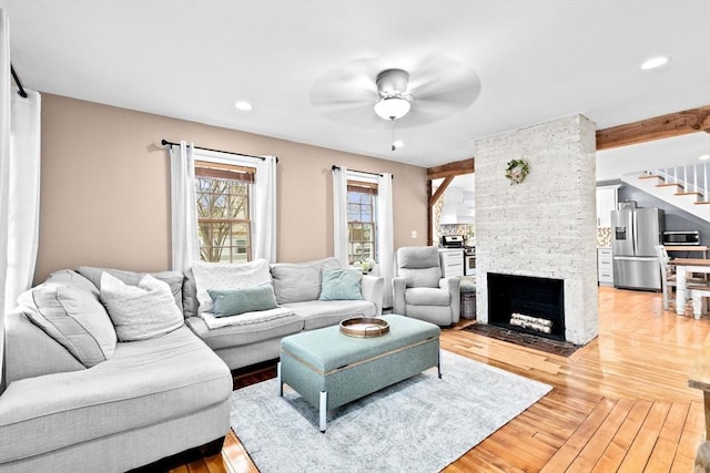 living room featuring recessed lighting, stairway, a brick fireplace, and light wood-style floors