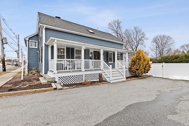 view of front of house with a shingled roof, a gate, fence, and a porch