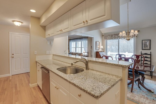 kitchen with dishwasher, light stone countertops, sink, and kitchen peninsula