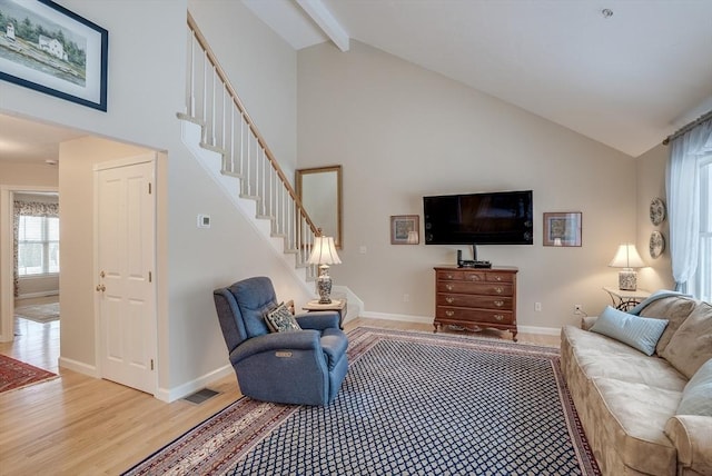 living room featuring beam ceiling, light hardwood / wood-style flooring, and high vaulted ceiling