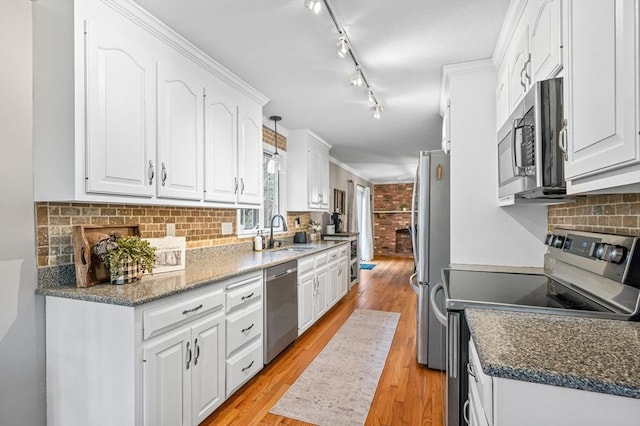 kitchen featuring light hardwood / wood-style flooring, white cabinets, appliances with stainless steel finishes, dark stone countertops, and sink