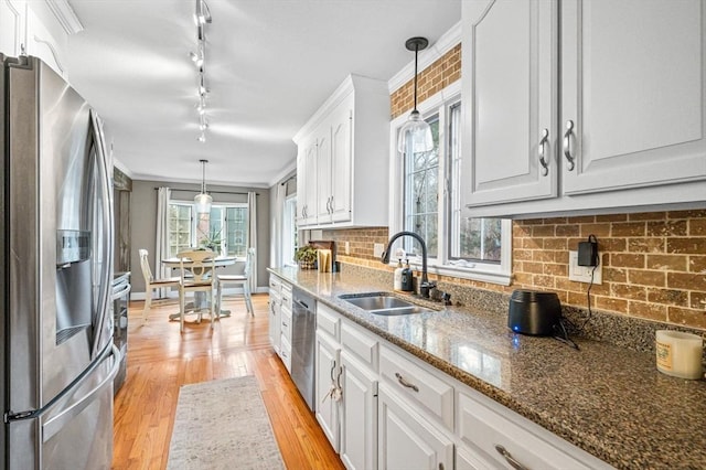 kitchen with stainless steel appliances, white cabinetry, sink, and crown molding