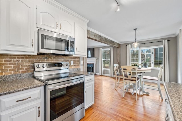 kitchen featuring stainless steel appliances, dark stone counters, white cabinets, and pendant lighting